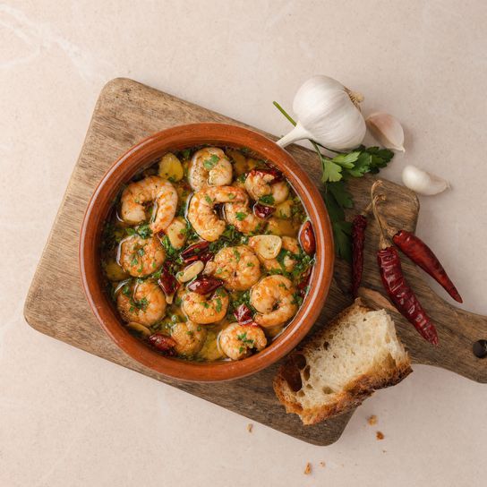 Prawns pil pil with garlic, chilli and parsley in a terracotta dish — a recipe from Dublin Cookery School.