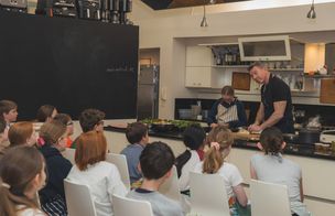 A tutor demonstrating knife skills and food preparation to a group of teenagers at Dublin Cookery School's Growing Gourmets teen cooking camp in Blackrock, Dublin