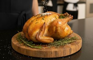 Chef seasoning a golden roast turkey with sea salt and herbs during a Christmas cooking class at Dublin Cookery School.