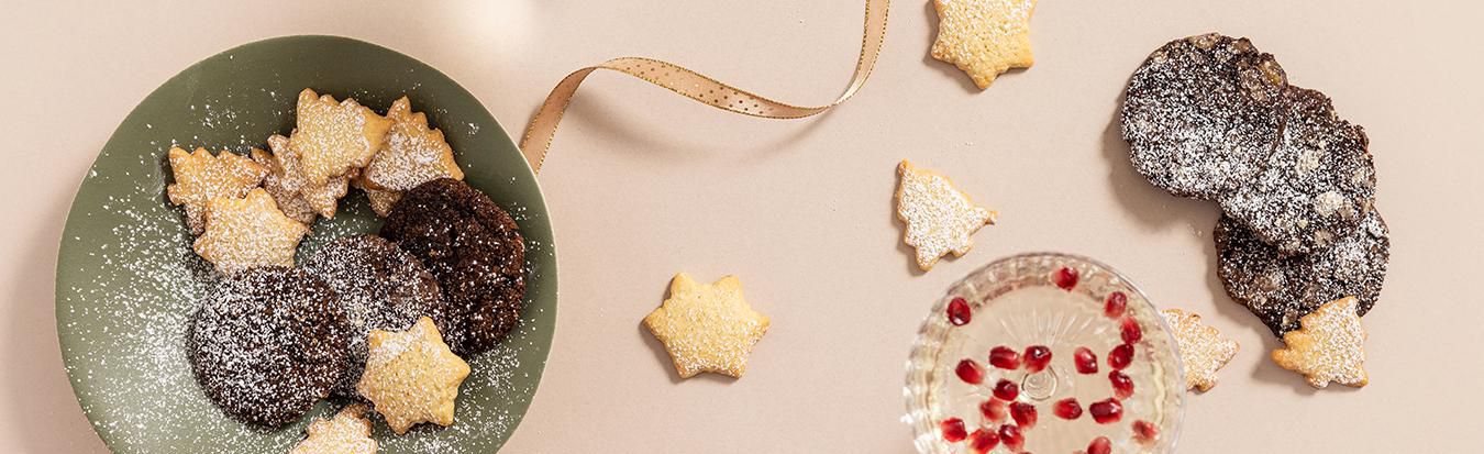 Plate of star-shaped Christmas biscuits and glasses of sparkling drinks with pomegranate seeds, styled for Dublin Cookery School’s festive season.