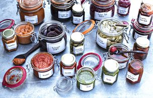 Shelf of glass jars filled with colourful fermented vegetables and preserves.