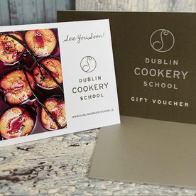 Dublin Cookery School digital gift voucher displayed on a tablet surrounded by Christmas decorations and wrapping materials.