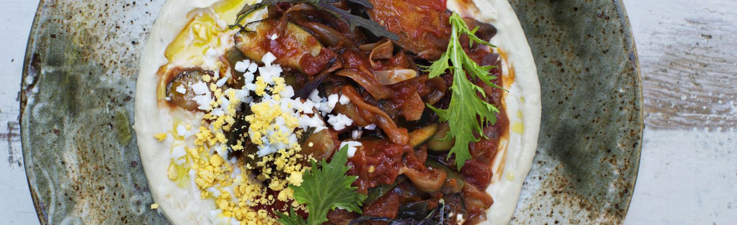 Close-up of hands demonstrating precision knife work at Dublin Cookery School, chopping fresh herbs on a wooden worktop.