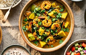 A prawn and mango curry in a ceramic bowl surrounded by rice, raita and cucumber salad — dishes from the Summer Curries evening class at Dublin Cookery School in Blackrock, Dublin